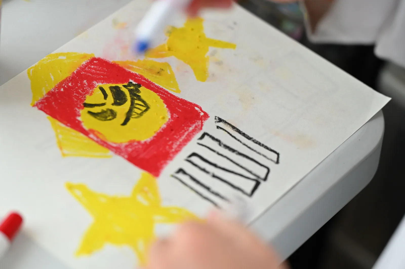 クレヨンで描いた作品と、描き進める子どもの手元