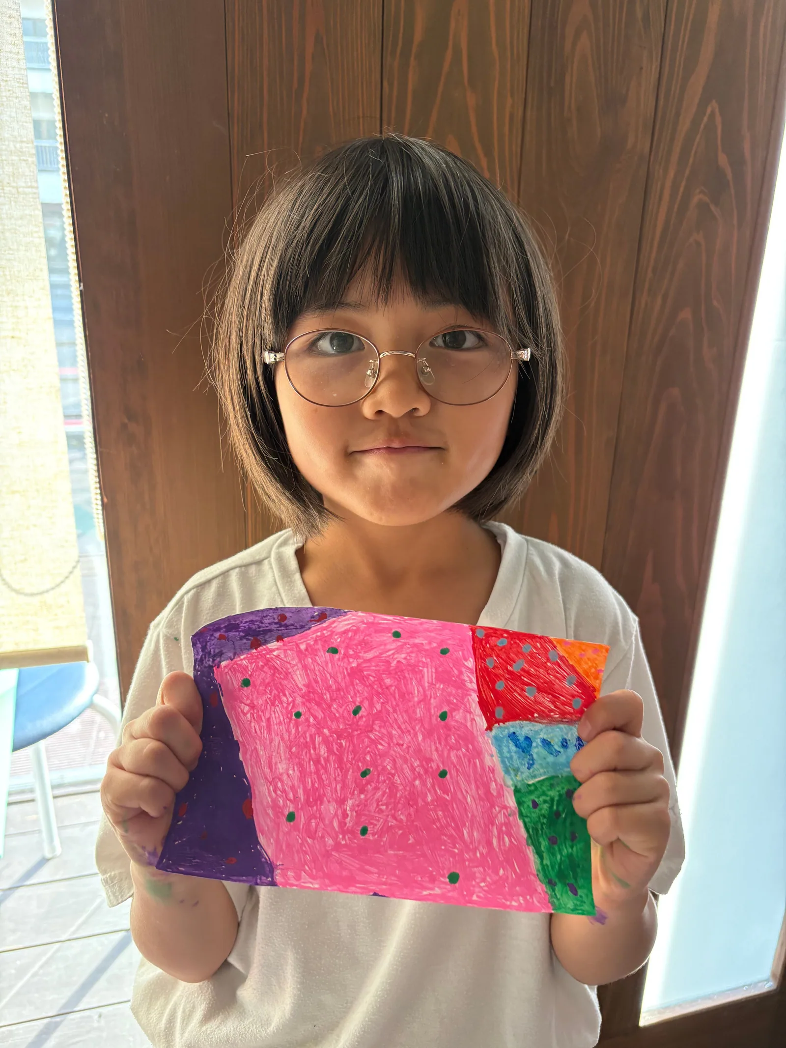自分でつくった色鮮やかな作品を見せる子ども